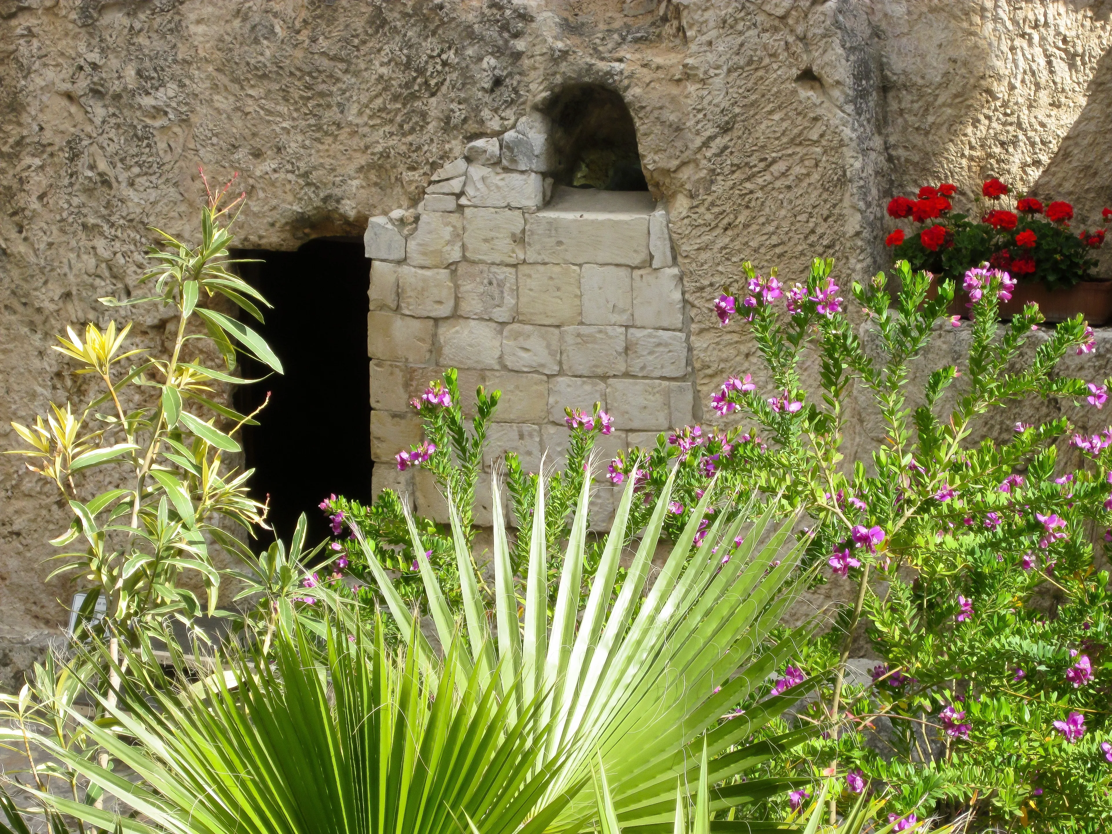 La entrada al sepulcro del huerto entre flores y plantas autóctonas.