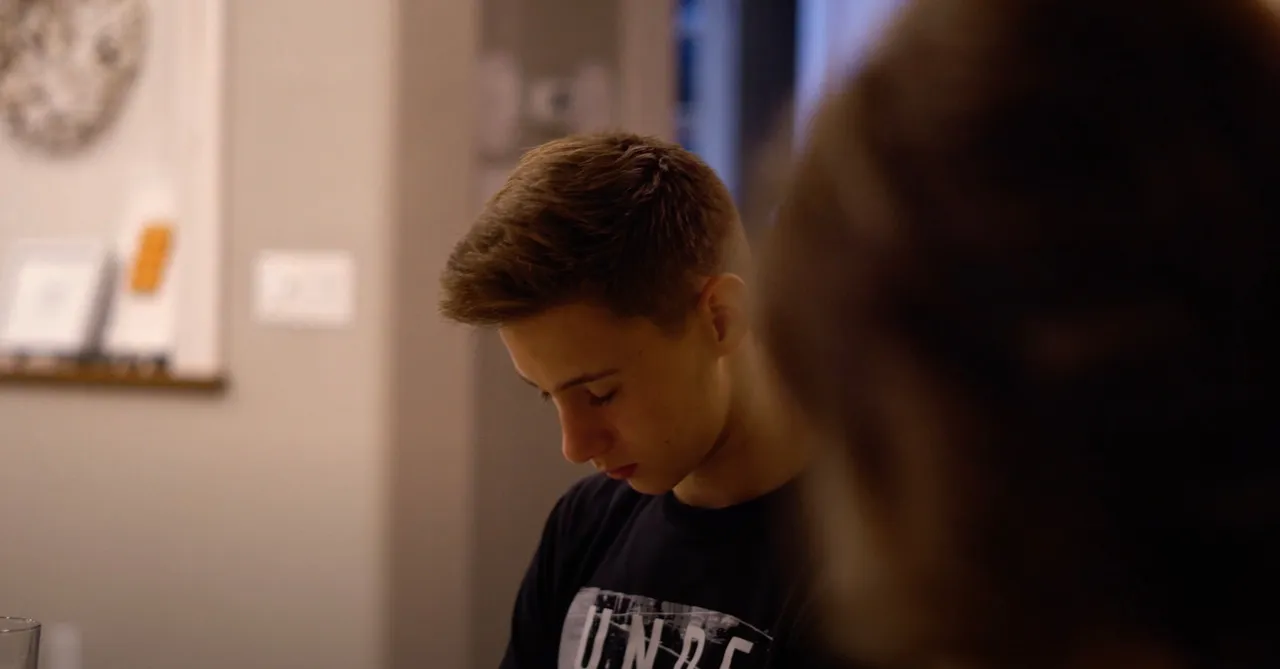 A teenager praying with his family