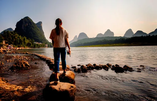 a woman using stepping stones to cross a river