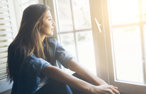 Young adult looking out a window