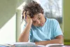 boy holding head over a book