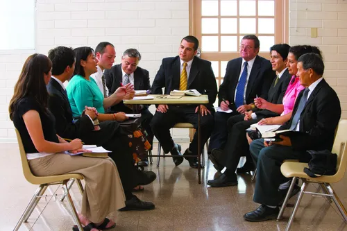 Men and women meeting together, possibly a ward council with the bishopric and ward leaders.