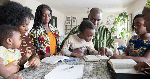Family of color reading scriptures together around a table.