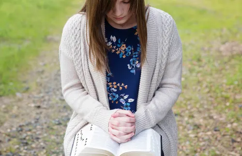 young woman reading her scriptures outdoors