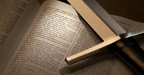 An unsheathed sword rests across an open set of the Doctrine and Covenants.