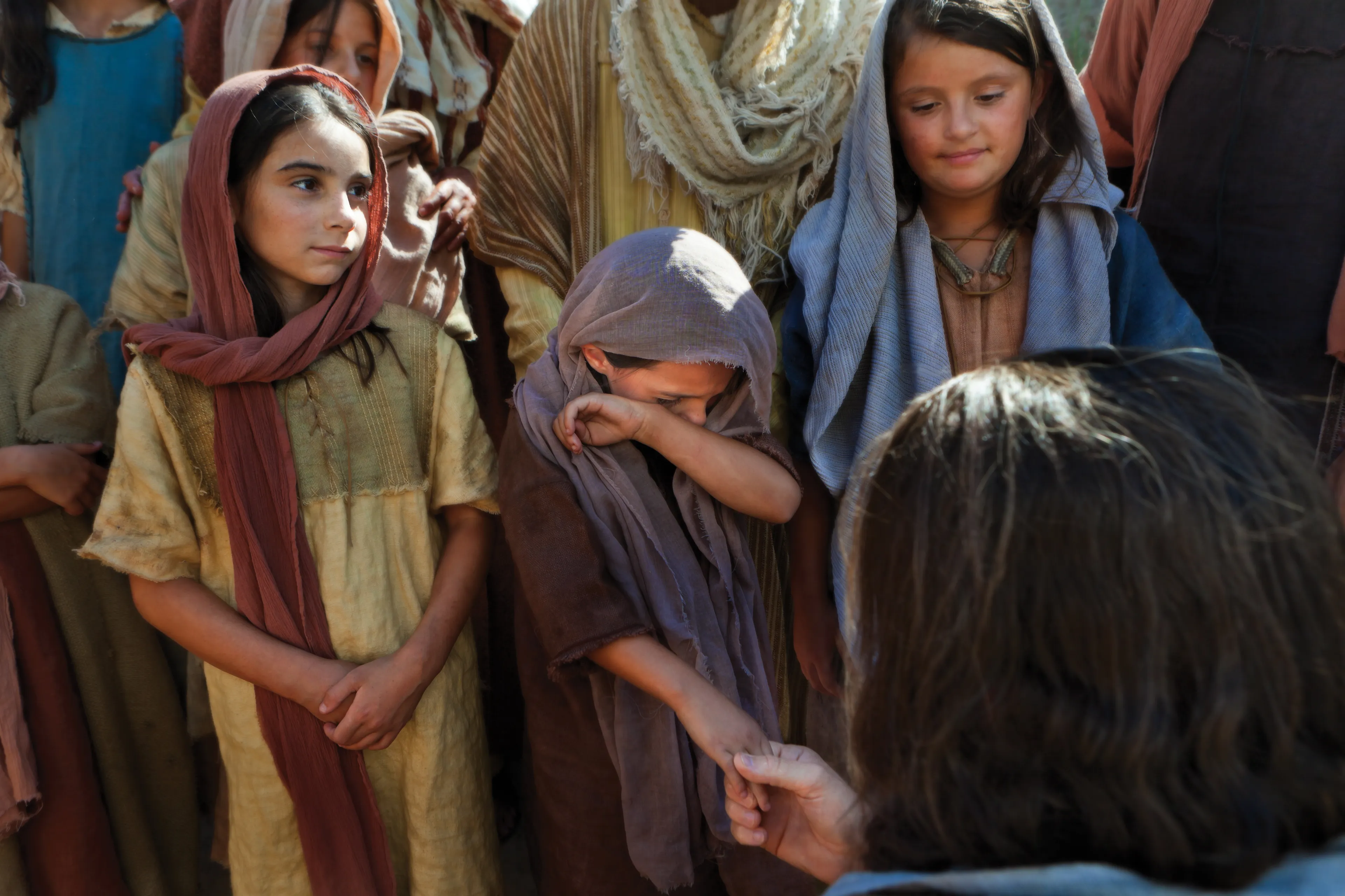Christ talks with a group of children, one of whom is crying.