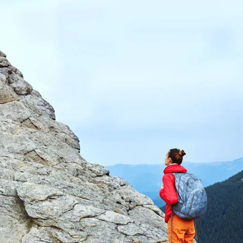 a young adult looking up at a mountain she’s trying to climb