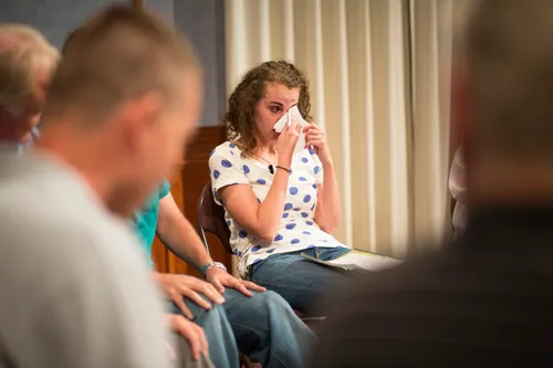 Men and women meeting together in an addiction recovery program.