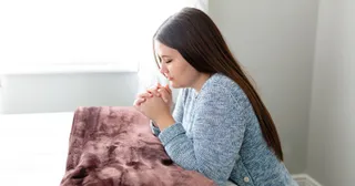 a woman kneels in prayer