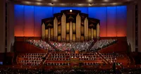 A crowd sits and watches the session inside the conference center. This is a wide shot taking in the audience and the choir. This is for the October 2018 General Conference.
