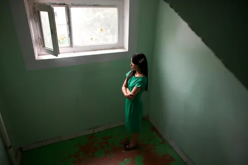 young woman standing by a window, looking out