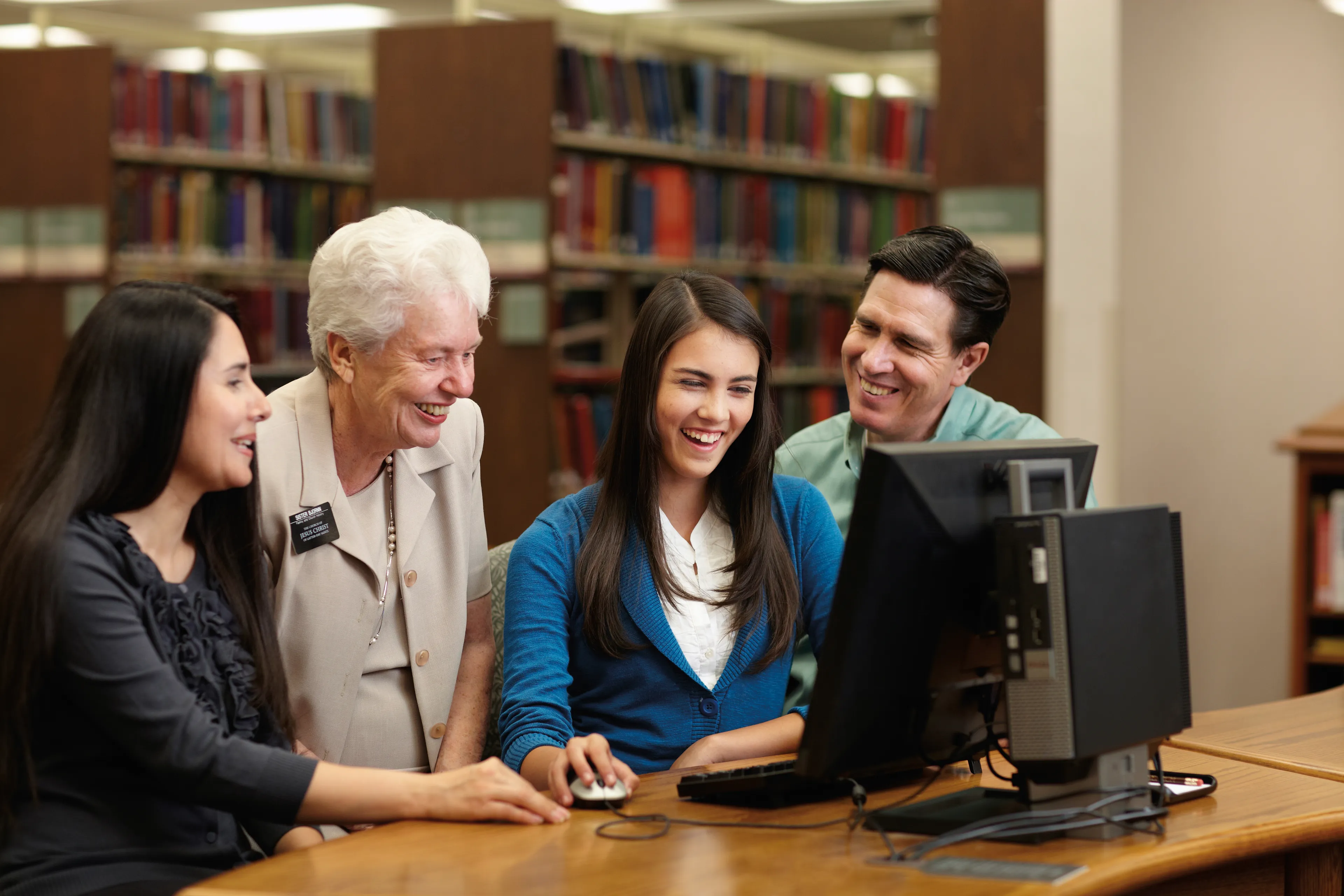 A senior sister missionary helps a family at the computer do family history research.