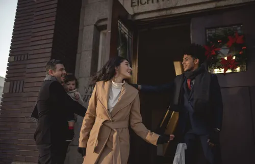 a man holding a door open for a family