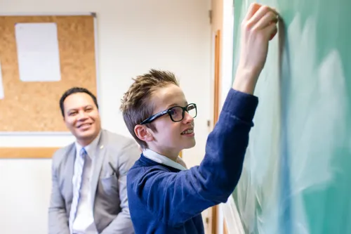 young man writing on chalkboard