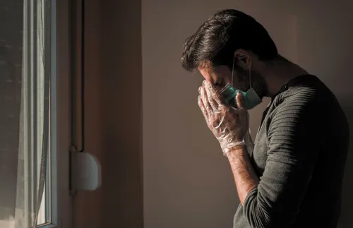 a man in a surgical mask bowing his head