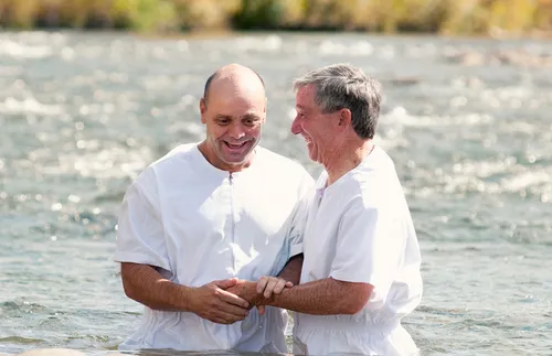 man being baptized in a lake