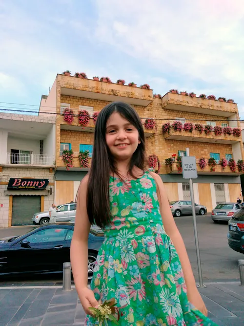 A young girl named Carmen Ahmad stands outside and smiles.