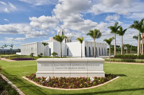 Exterior of the Brasilia Brazil Temple. It features the temple, the temple sign, and trees nearby. Image was taken during the day.