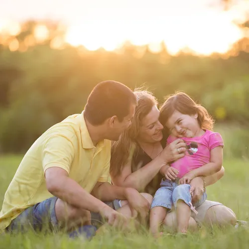 mother, father, and little girl sitting outdoors