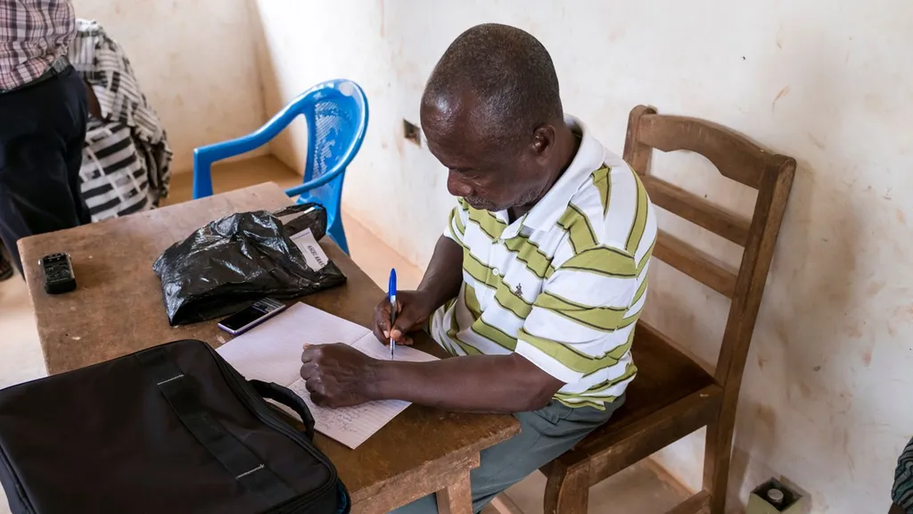 A man writes something down in a notebook.
