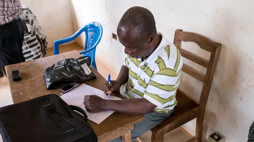 A man writes something down in a notebook.