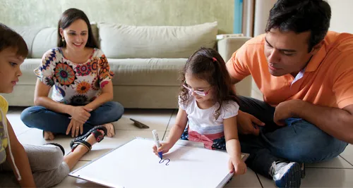 young girl coloring with family