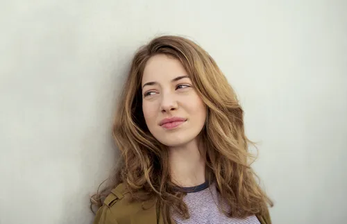 young adult woman leaning against a wall