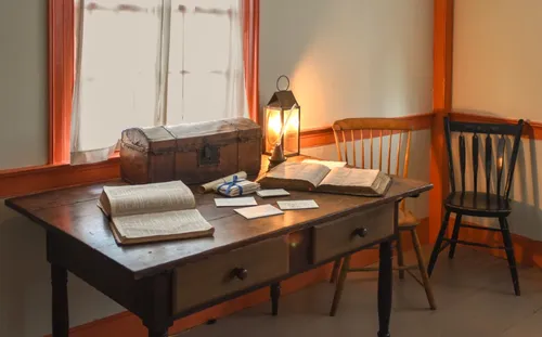 bedroom with a desk and several chairs, bright orange casings surrounding the windows