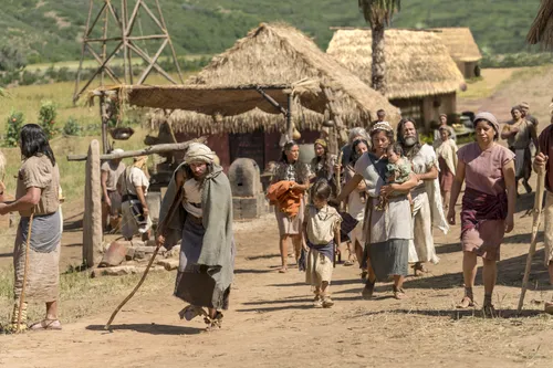 A disabled man walks in city streets with other Nephites.