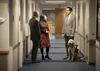Man with service dog talks with others in hallway
