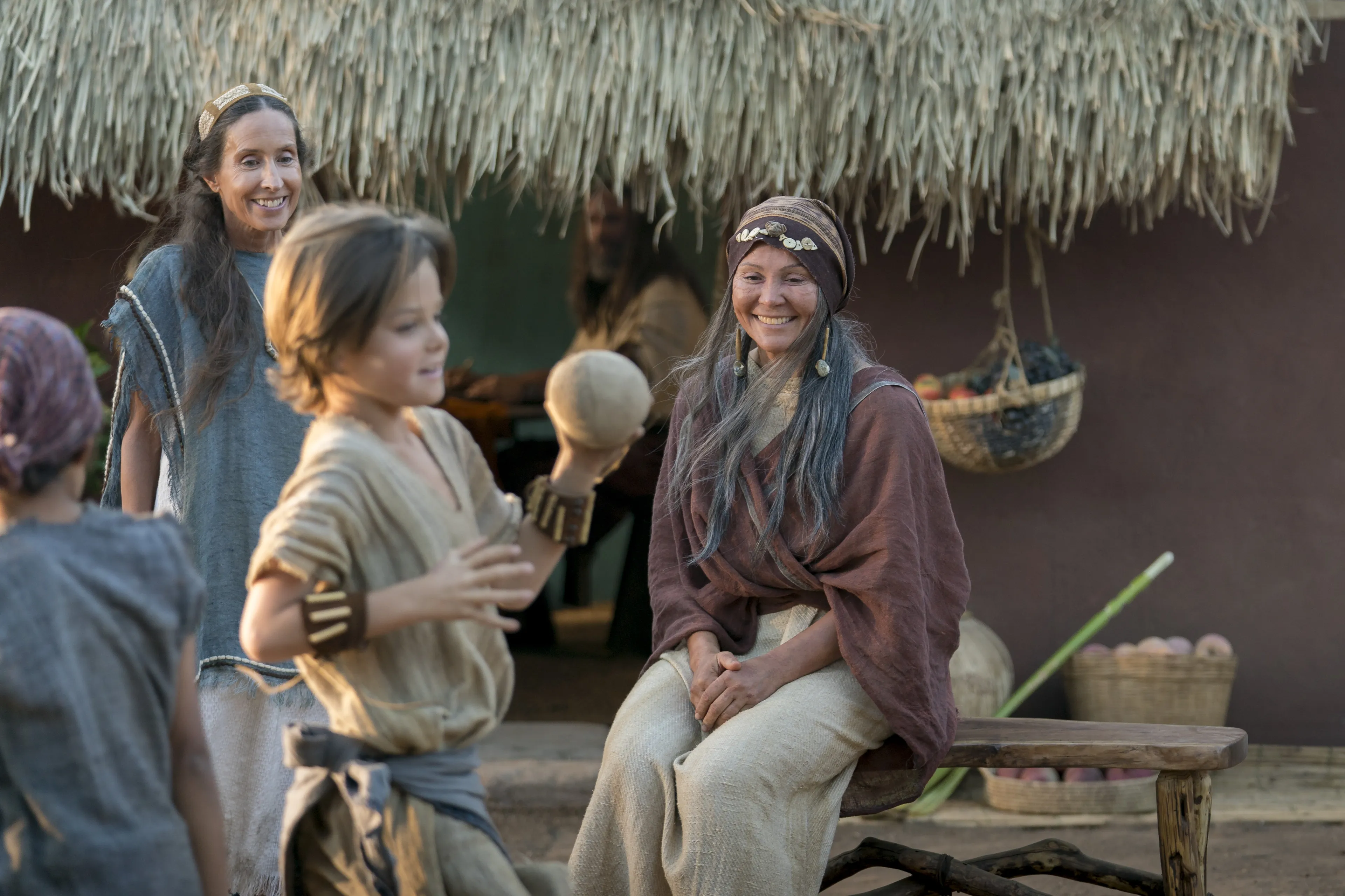 Nephi's wife sits outside with the children as they play.