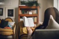 A young woman sits on her couch studying the gospel of Jesus Christ in the Bible