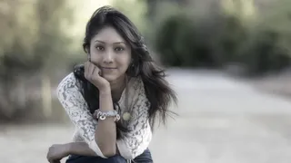 Beautiful Latin Young Woman sitting by side of road