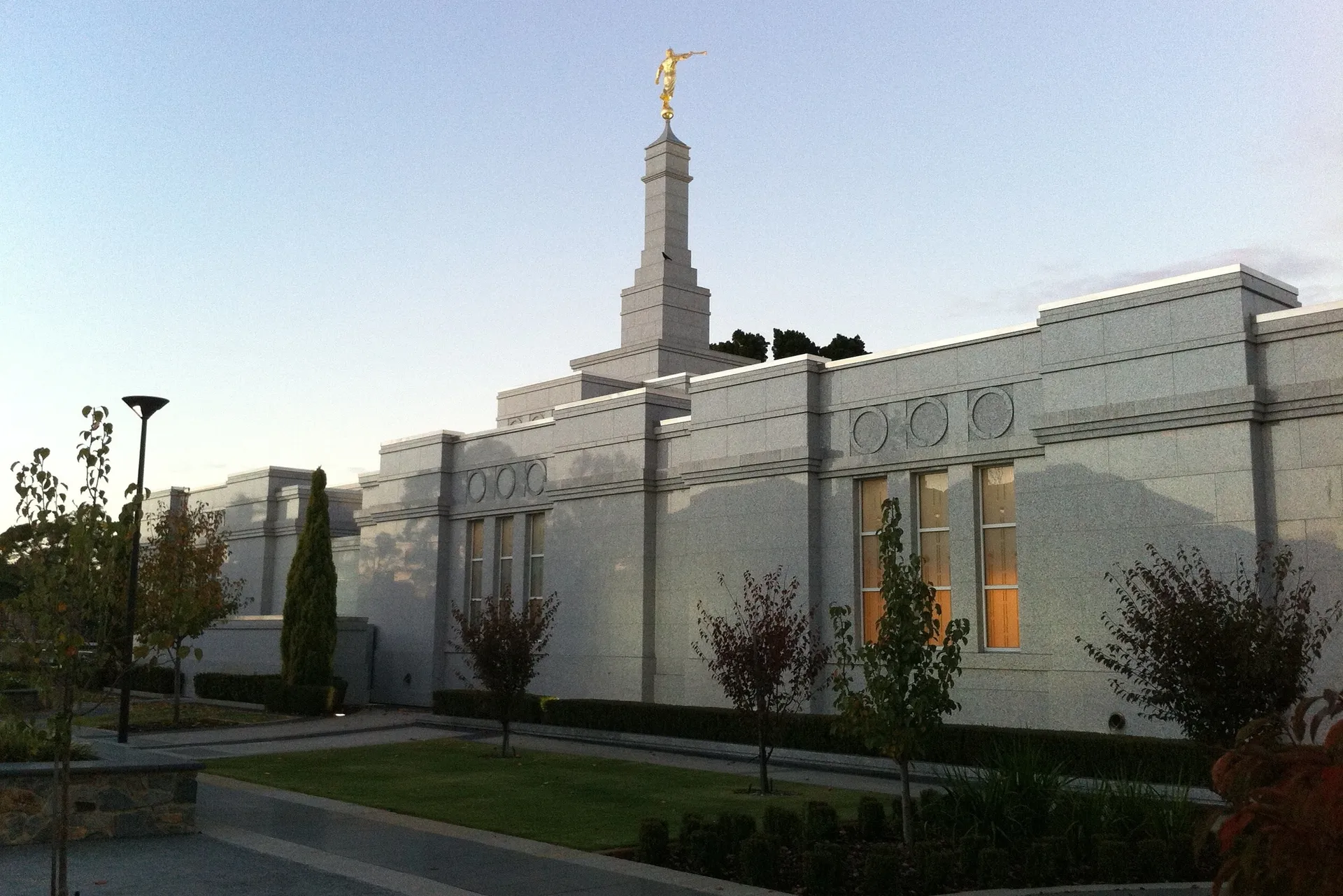 The Perth Australia Temple in the evening, including the spire and exterior of the temple.