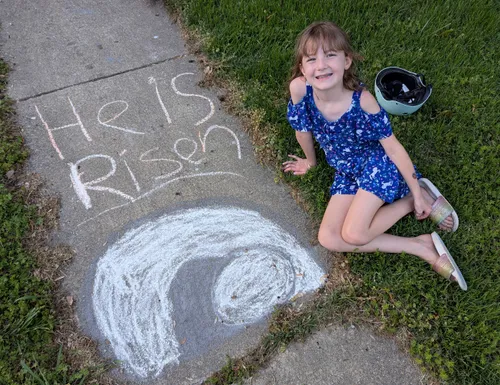 Smiling girl sitting near sidewalk art of the Savior’s empty tomb