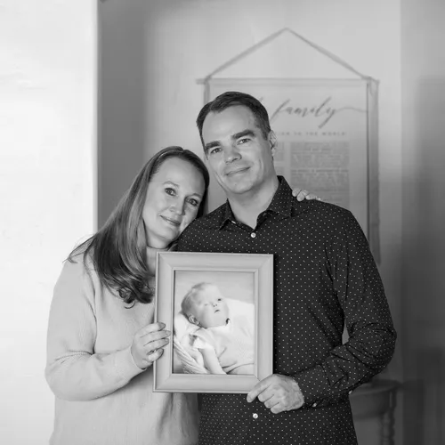 husband and wife holding a picture of their son