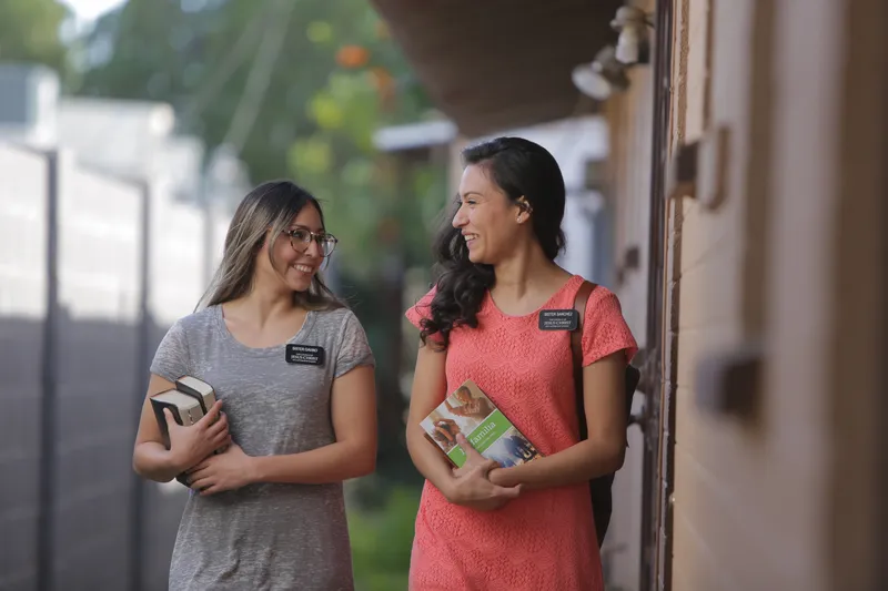 Two sister missionaries walk down the street looking for people to teach about the Book of Mormon and Jesus Christ