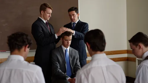a young man being ordained to the priesthood by the laying on of hands