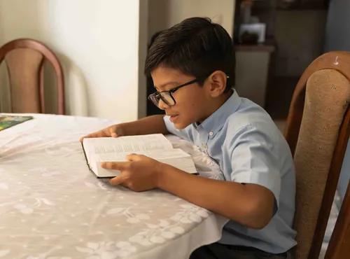 Boy sitting at a table and reading the scriptures