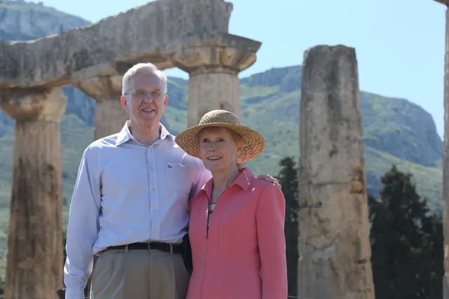 Elder D. Todd Christofferson and his wife Kathy standing in front of some ruins in Corinth, Greece.