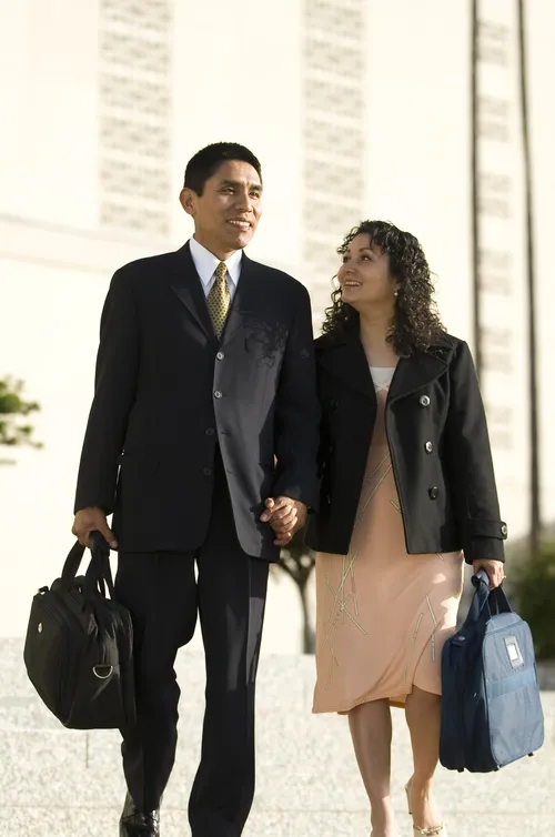 An Hispanic couple with temple bags walking outside the Los Angeles California Temple.
