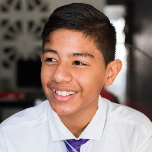 a young man wearing a white shirt and purple tie; he is smiling