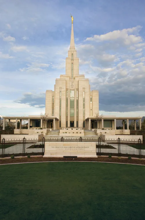 A front view of the Oquirrh Mountain Utah Temple, with the temple’s granite sign and black fence along the front.
