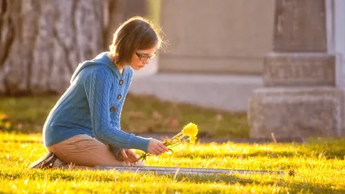 a young woman placing flowers on a grave