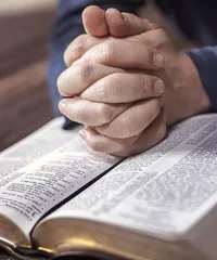 Hands folded lay on the Bible open to Beatitudes