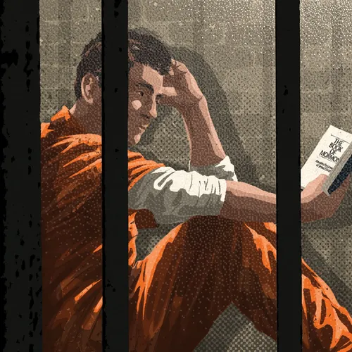 man in a prison cell reading a book