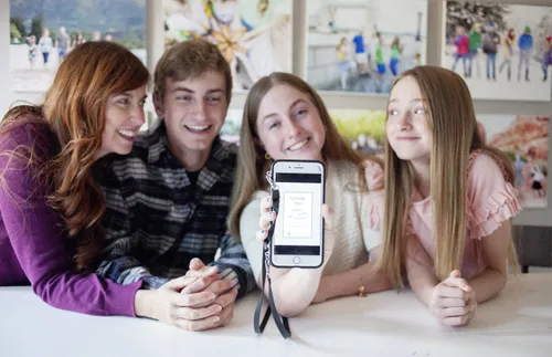 young woman holding up phone as others look on
