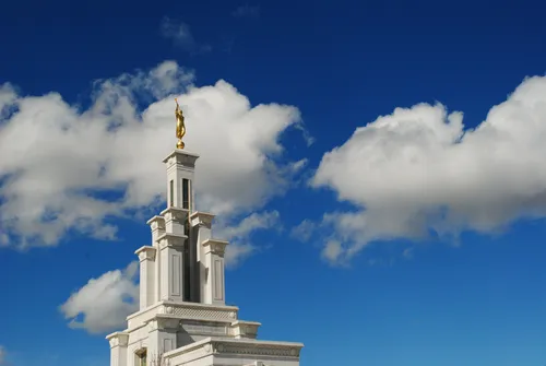 The spire on top of the Columbia River Washington Temple, with a deep blue sky and clouds in the background.