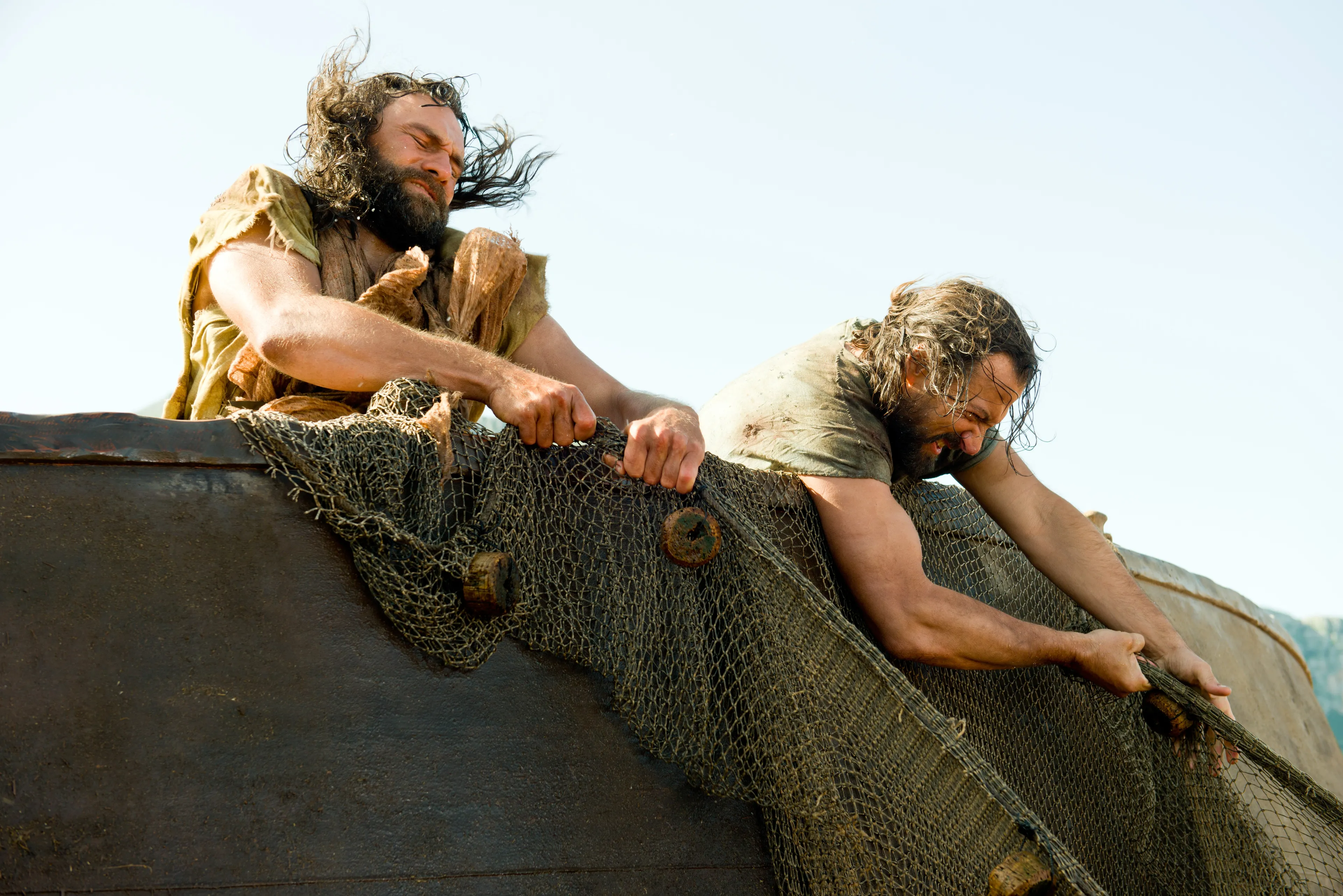 From the shore, Christ tells the disciples to cast their net on the right side of the ship, and when they did, there was an abundance of fish.