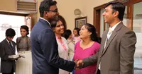 Members are shaking hands and greeting each other in a foyer of a meetinghouse in India.